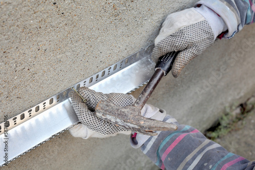 Tableau sur toile Worker placing aluminum batten for styrofoam insulation to wall