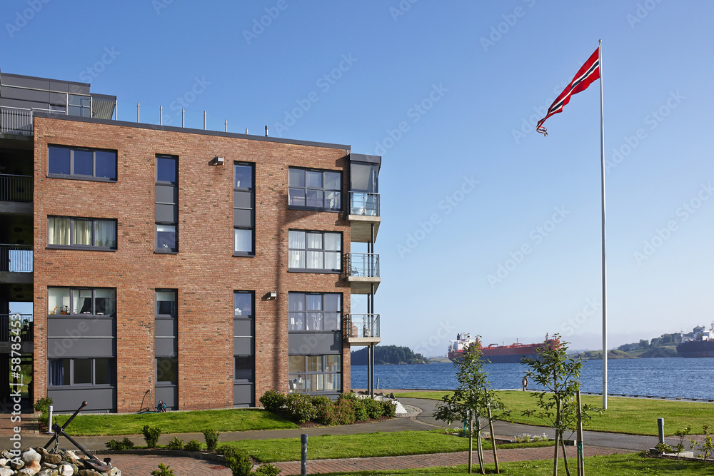 Modern five-storey house on the sea shore with Norwegian flag