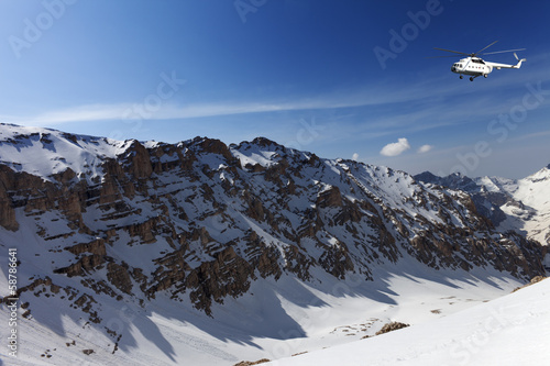 Helicopter in snowy sunny mountains photo