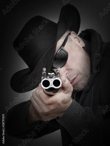 Angry gangster with shotgun aiming at you. Gun control concept.