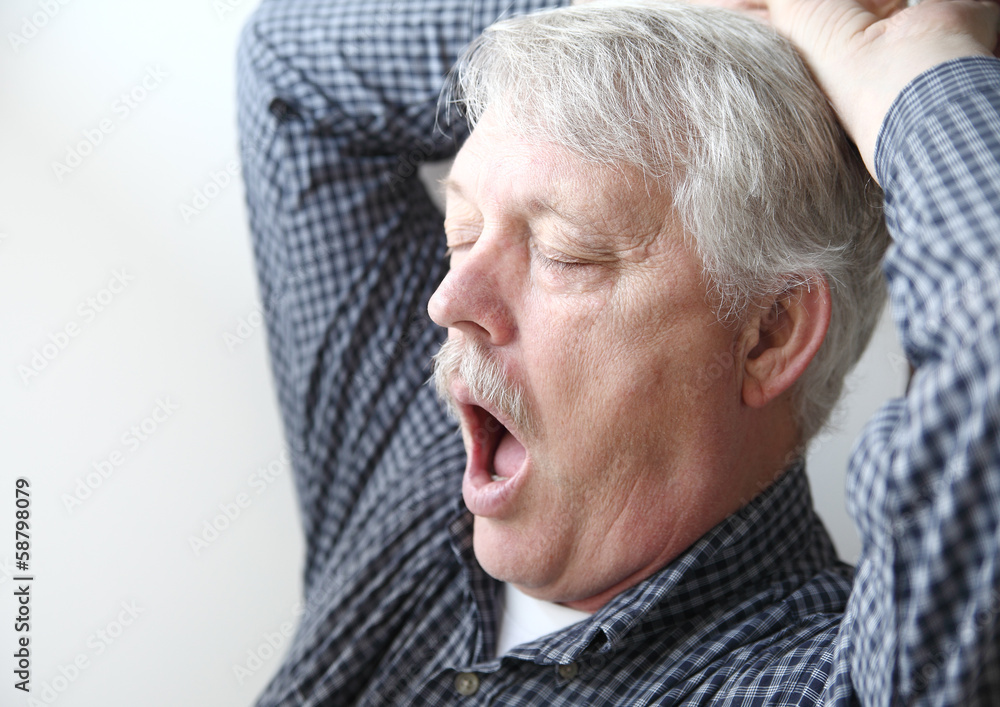 Obraz premium tired senior man stretches and yawns