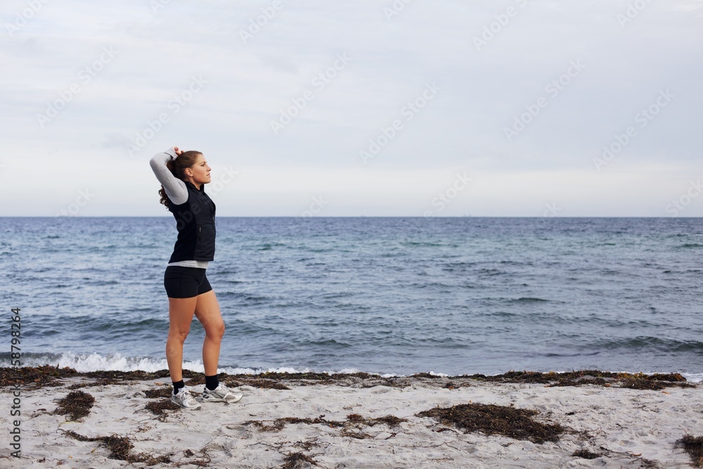 Sporty fitness woman standing on beach after workout