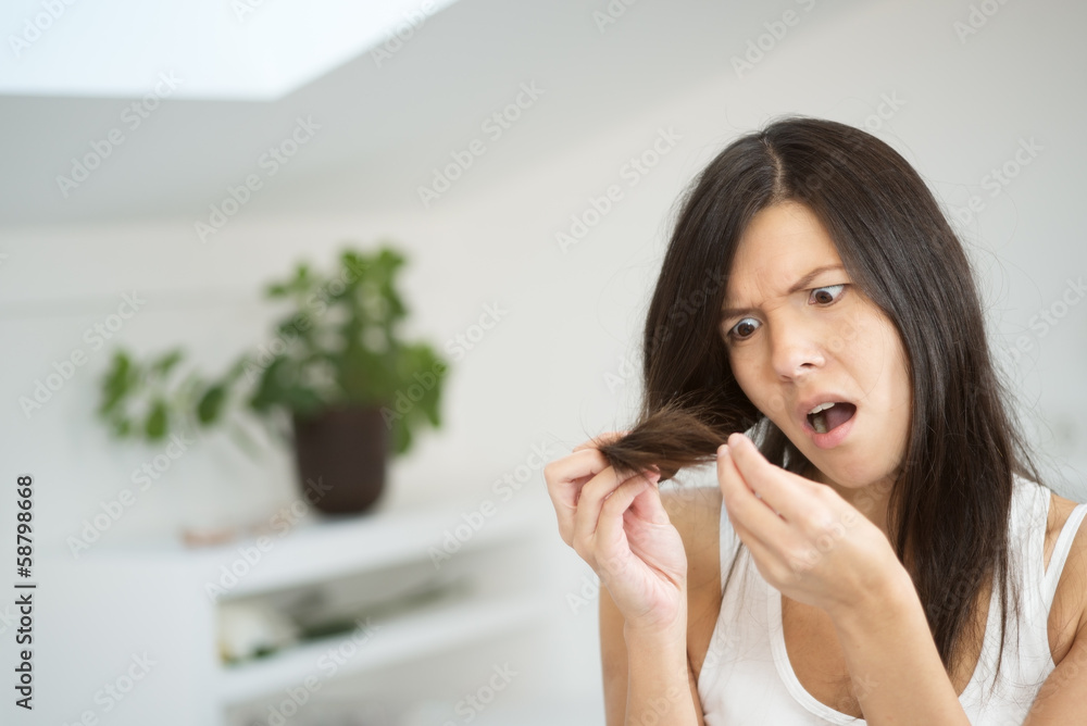 Woman checking the end of her hair for split ends Woman checking the end of her hair for split ends