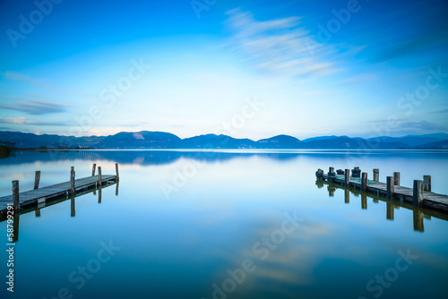 Two Wooden pier or jetty and on a blue lake sunset and sky refle