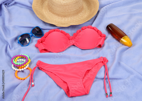 Swimsuit and beach items on purple background