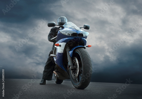Man seat on the motorcycle under sky with clouds © Andrii IURLOV