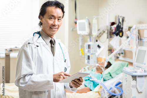 Doctor With Digital Tablet Examining Patient's Test Report