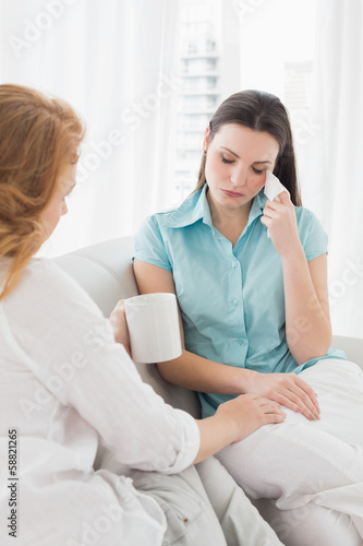 Woman consoling a crying female friend at home