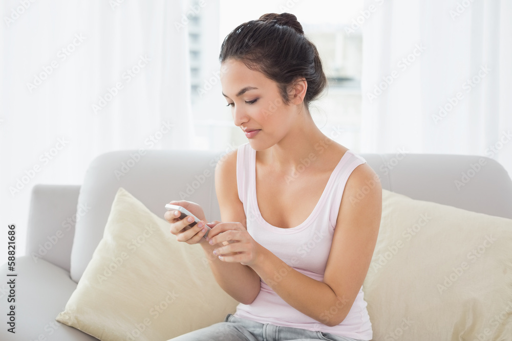Relaxed young woman text messaging on sofa at home Relaxed young woman text messaging on sofa at home