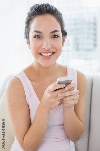 Young woman text messaging on sofa at home