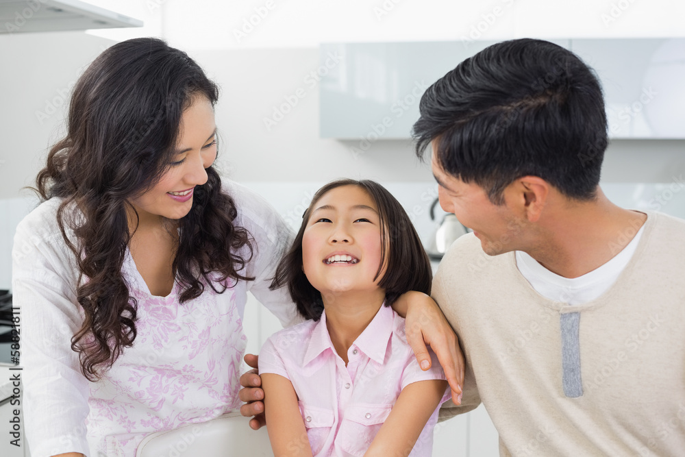 Smiling couple with a cheerful daughter in kitchen Smiling couple with a cheerful daughter in kitchen