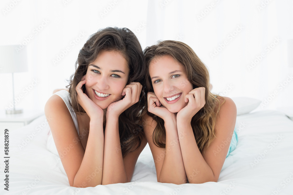 Two smiling young female friends lying in bed Two smiling young female friends lying in bed