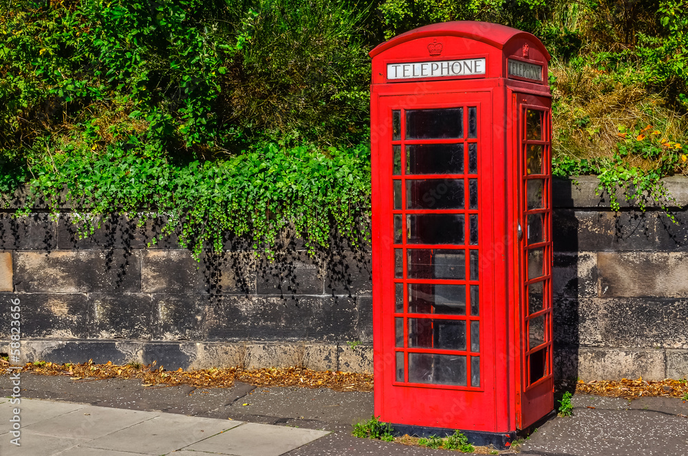 Typical red English telephone booth in the park Typical red English telephone booth in the park