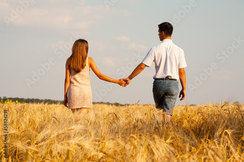 inlove couple walking through wheat field