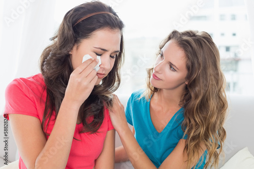 Woman consoling a crying female friend at home