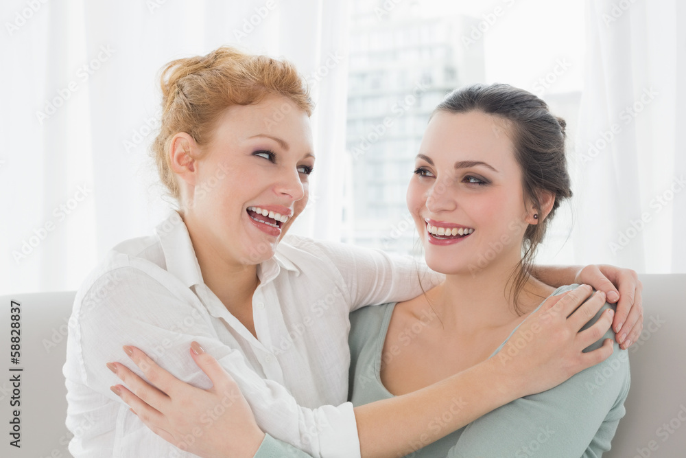 Cheerful female friends embracing in living room Cheerful female friends embracing in living room