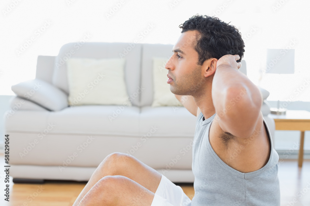 Young man doing abdominal crunches in the living room Young man doing abdominal crunches in the living room