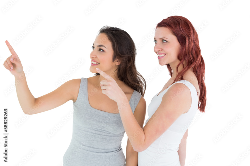Two young female friends pointing away Two young female friends pointing away