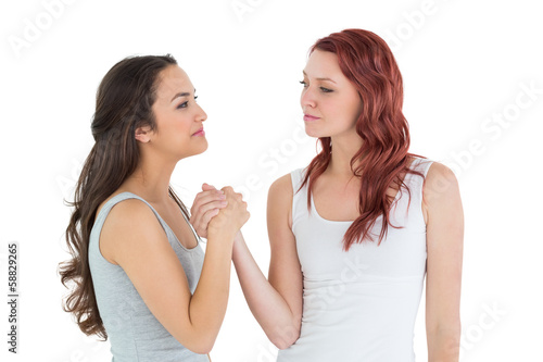 Two casual young female friends arm wrestling
