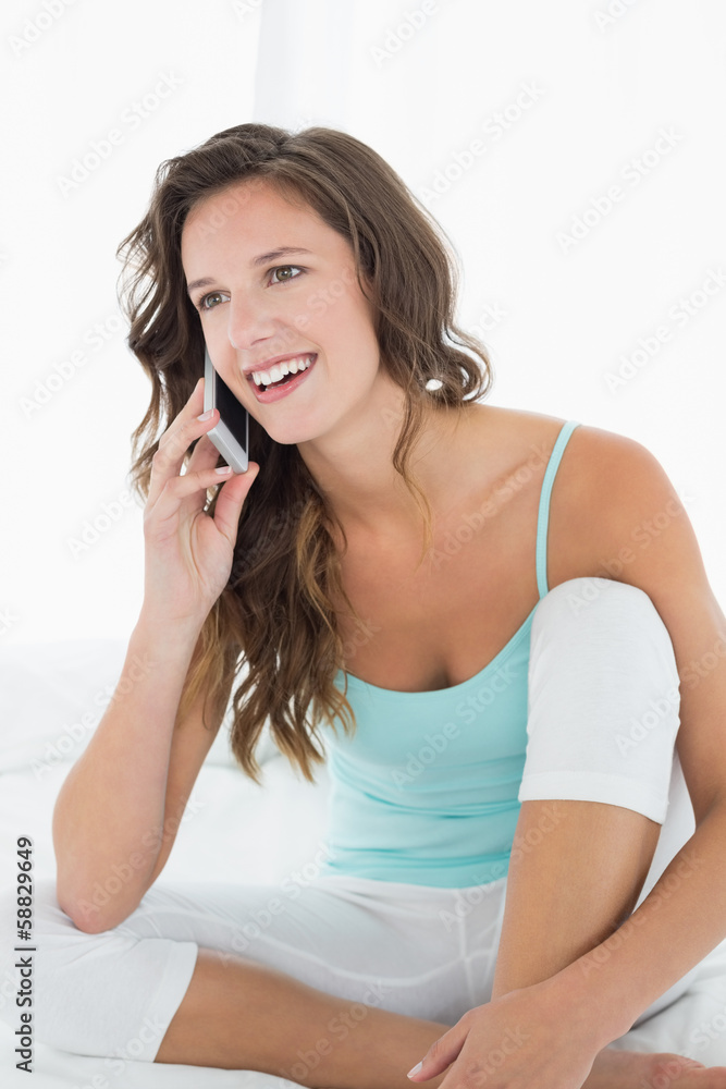 Naklejka premium Woman in tank top using mobile phone in bed