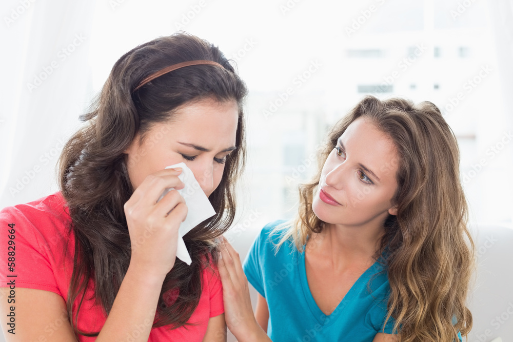 Woman consoling a crying female friend at home Woman consoling a crying female friend at home