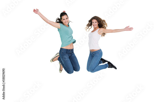 Two cheerful young female friends jumping