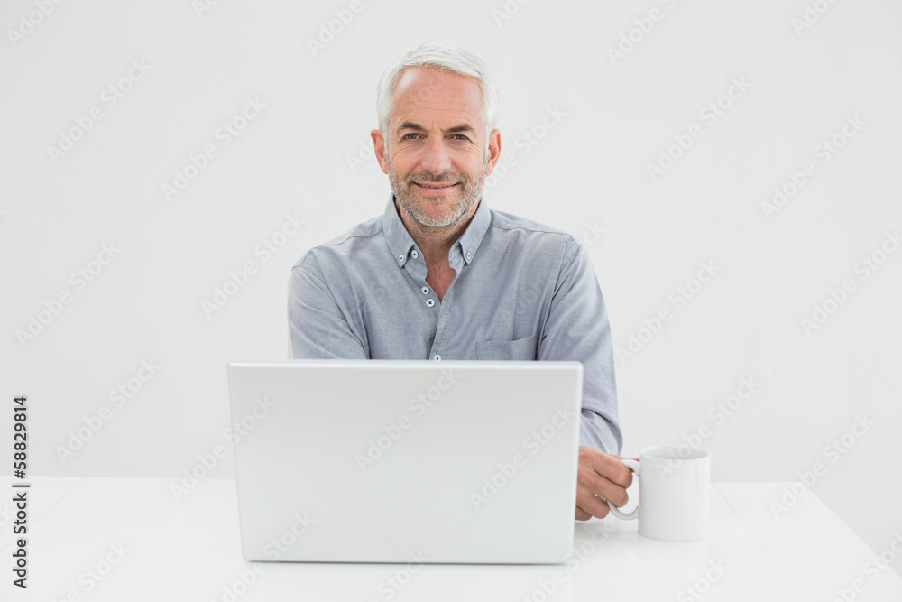 Smiling mature businessman with laptop and coffee cup Smiling mature businessman with laptop and coffee cup