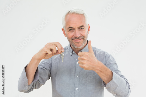Portrait of a smiling mature man with keys gesturing thumbs up
