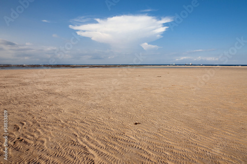 Ocean and beach with yellow sand and cloud in sky