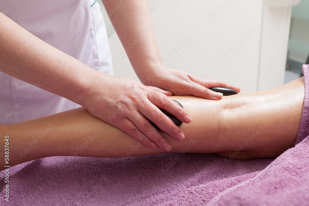Spa. Female legs having hot stone massage. Bodycare and relax.