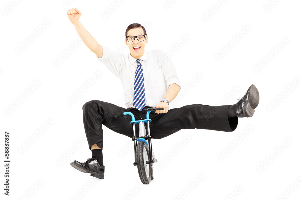 Excited young businessman riding a small bicycle and gesturing h Excited young businessman riding a small bicycle and gesturing h