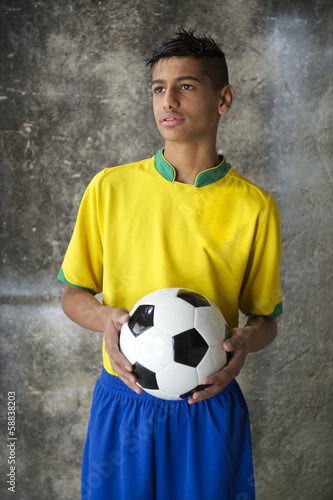 Young Brazilian Soccer Player in Uniform Holds Football