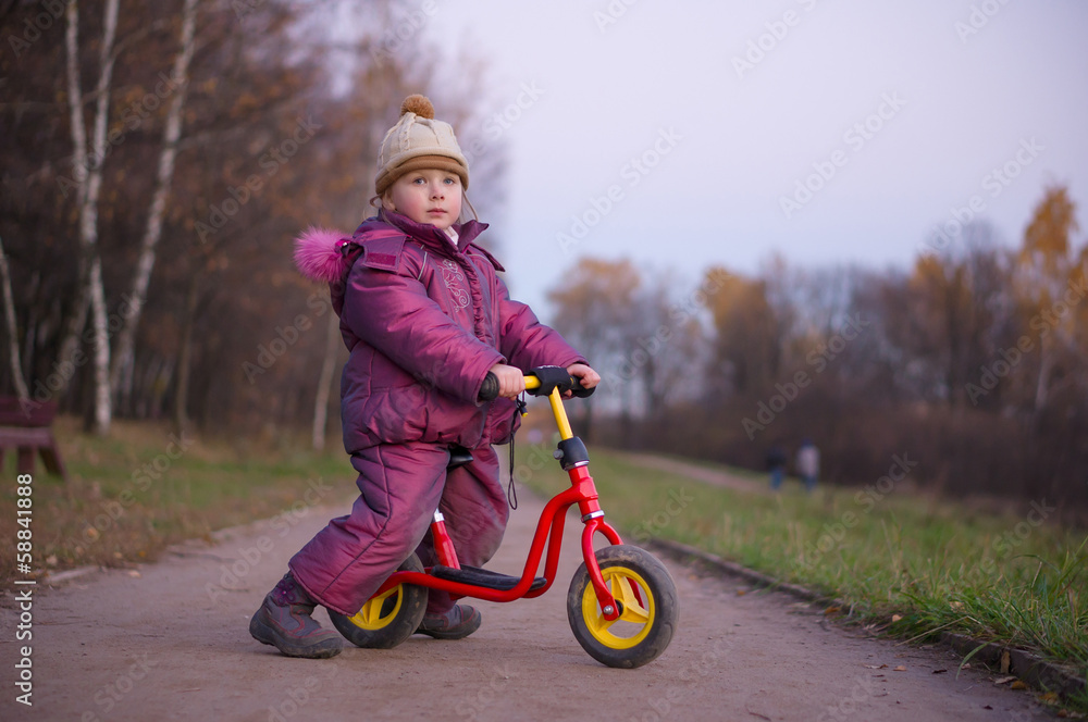 Adorable girl ride on learner bike in autumn park Adorable girl ride on learner bike in autumn park