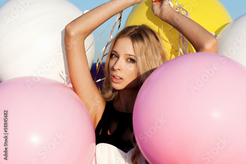 Happy young woman with colorful latex balloons