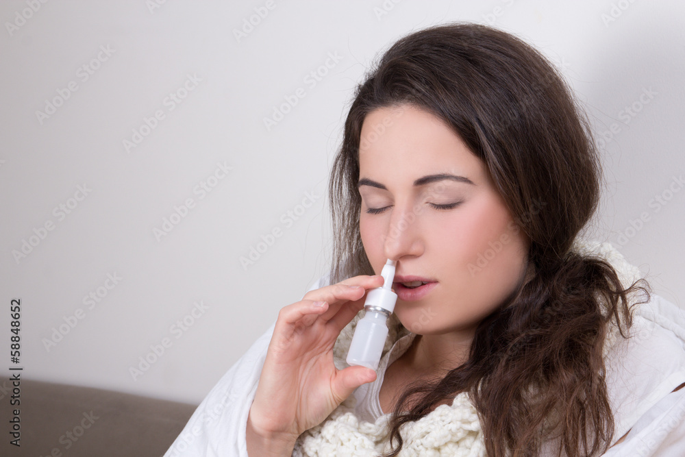 woman using nasal spray in her living room woman using nasal spray in her living room