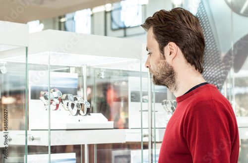 Man looking at shop window or display case in shopping center