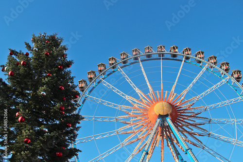 Christmas tree and ferris wheel on a blue sky