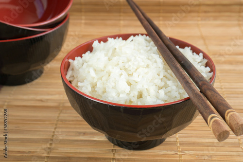 White steamed rice in the bowl with wooden chopsticks