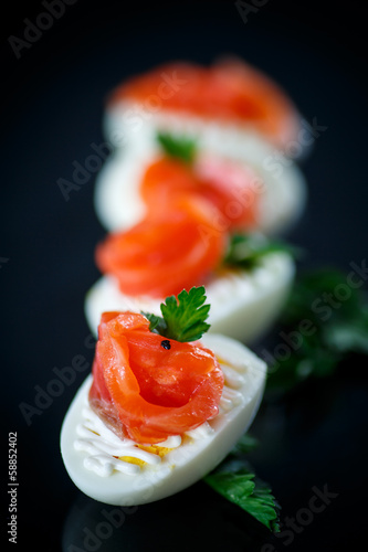 boiled egg with salty salmon on black background photo