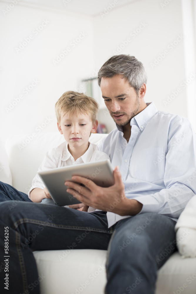 father and son playing on a tablet father and son playing on a tablet