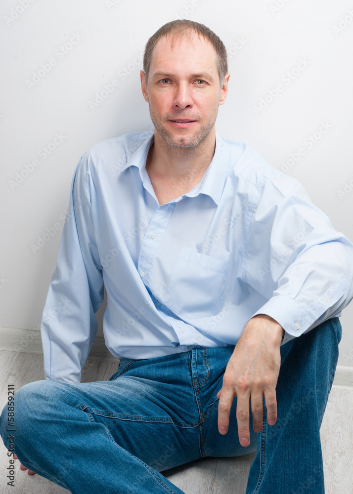 portrait of confident man in blue sitting on the floor portrait of confident man in blue sitting on the floor
