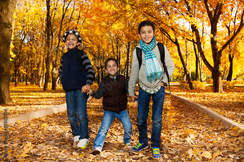 Three kids walk in autumn park