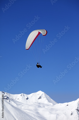 Paraglider in snowy winter mountains