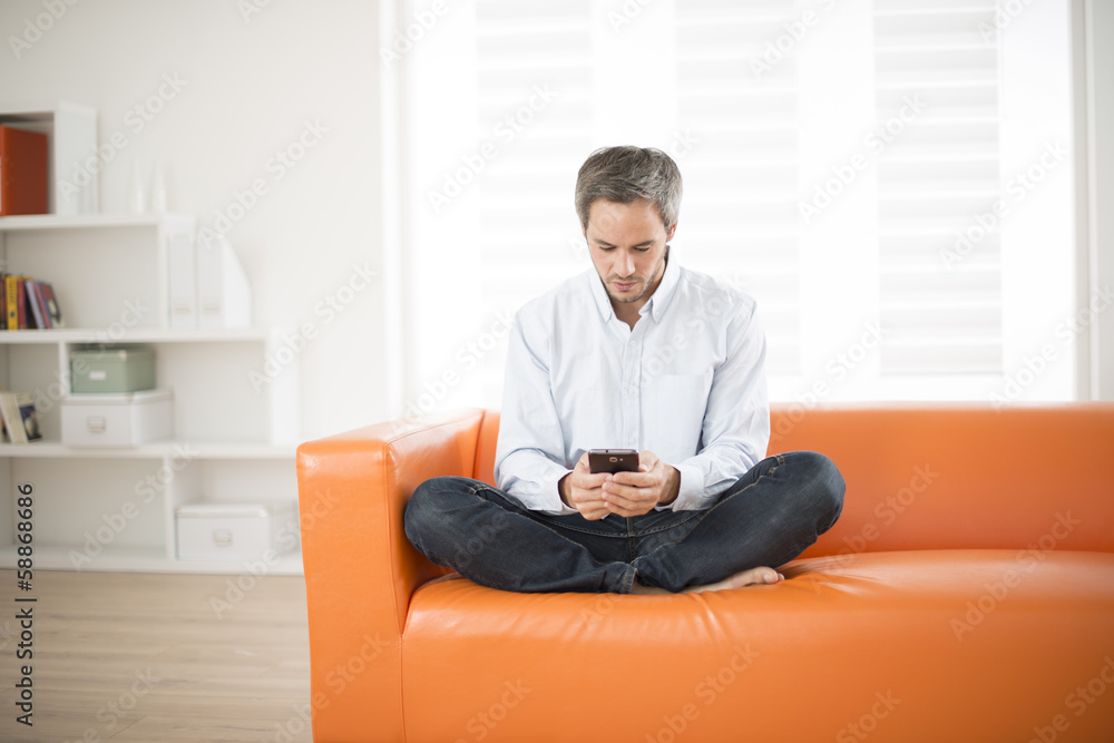 attractive man smiling and phone on a couch
