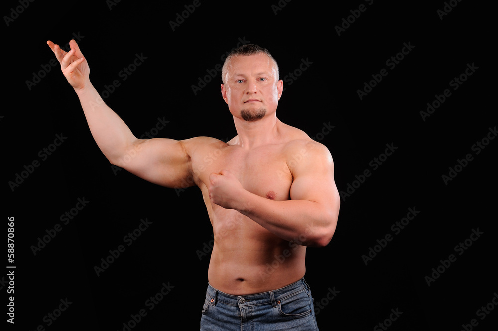 Muscular male posing on black background