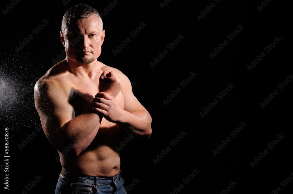 Muscular male posing on black background