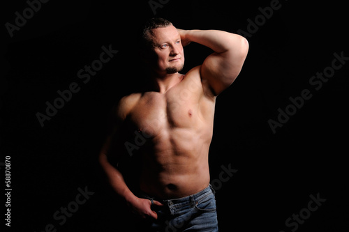 Muscular male posing on black background © Art_man