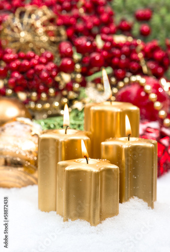 advent decoration in gold and red with four burning candles