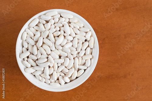 White beans on a bowl, on wooden background