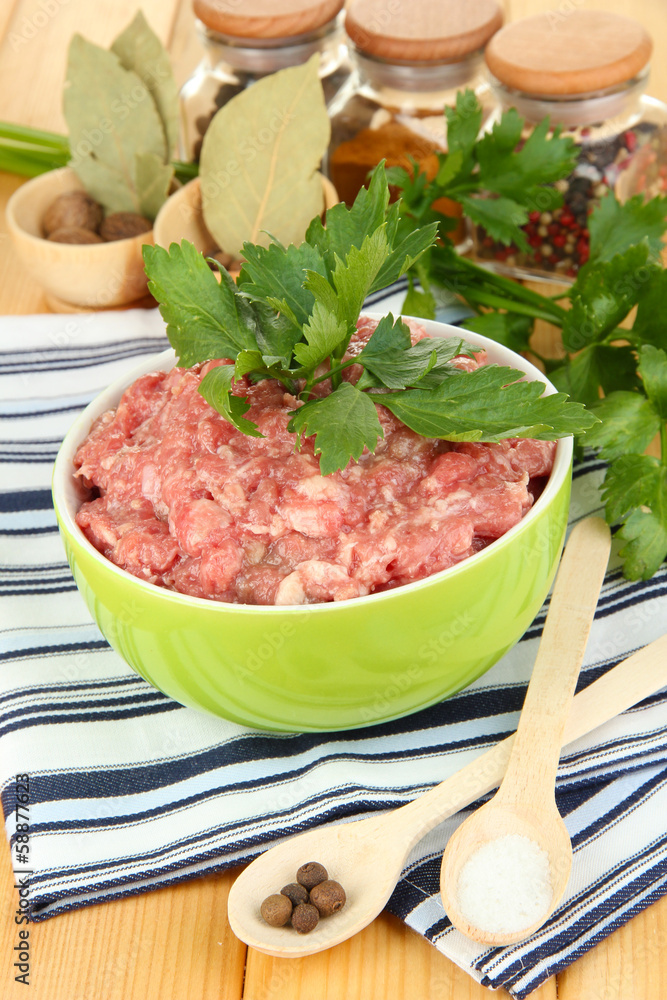 Bowl of raw ground meat with spices on wooden table Bowl of raw ground meat with spices on wooden table